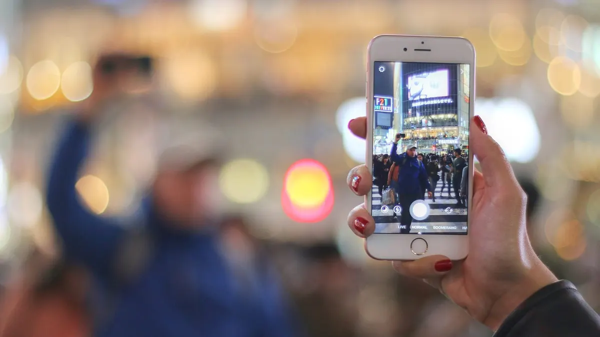 夜の街でスマートフォンを掲げ、カメラで街並みを撮影している手元